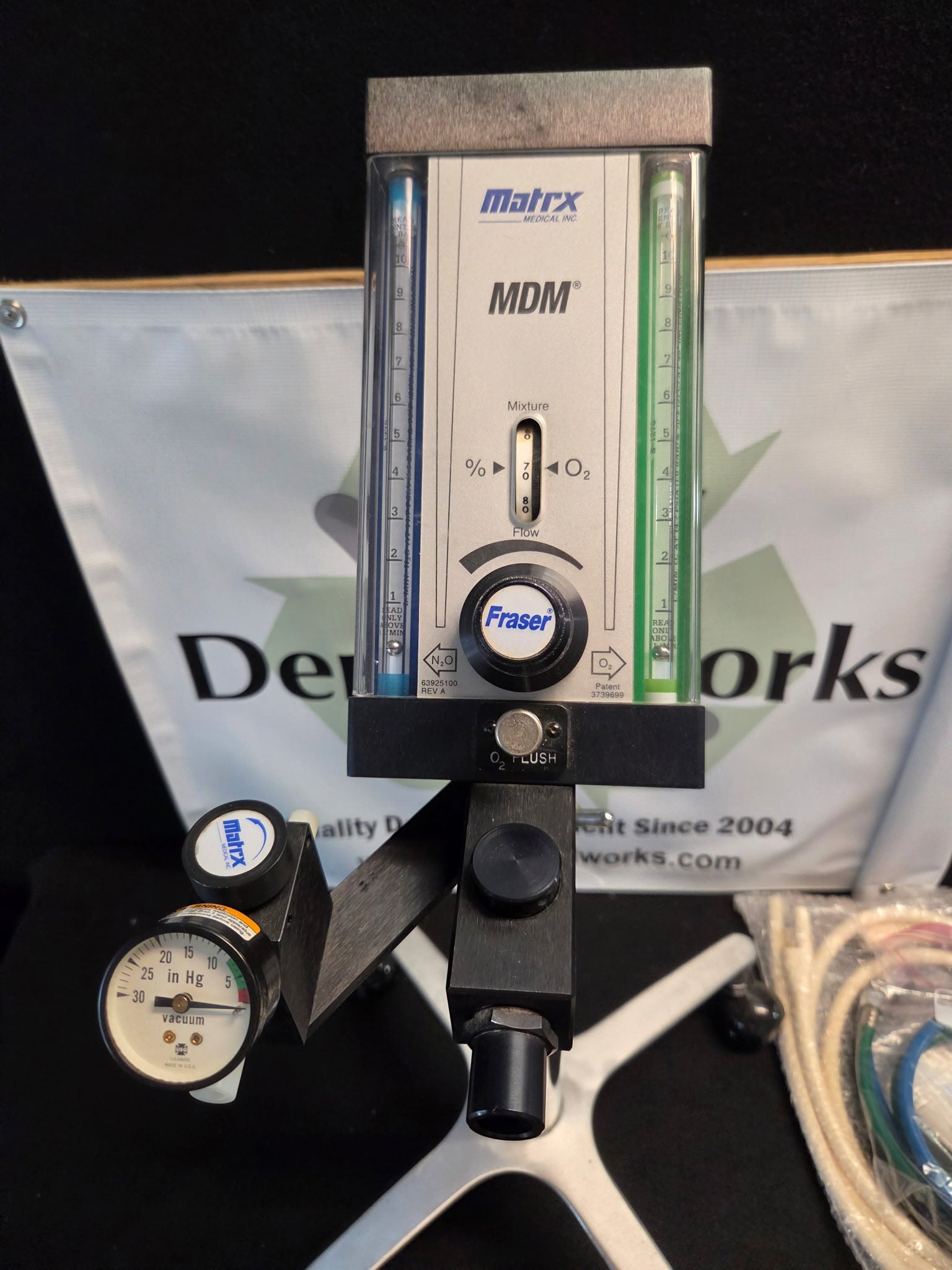 Close view of the Matrx MDM flowmeter face showing dual glass flow tubes, mixture dial, flow control knob, oxygen flush bar and scavenger vacuum gauge