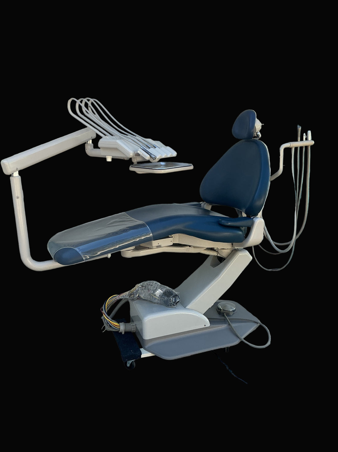 A-dec Cascade 1040 chair in navy upholstery with radius-arm delivery and assistant arm, photographed against a blacked-out background.