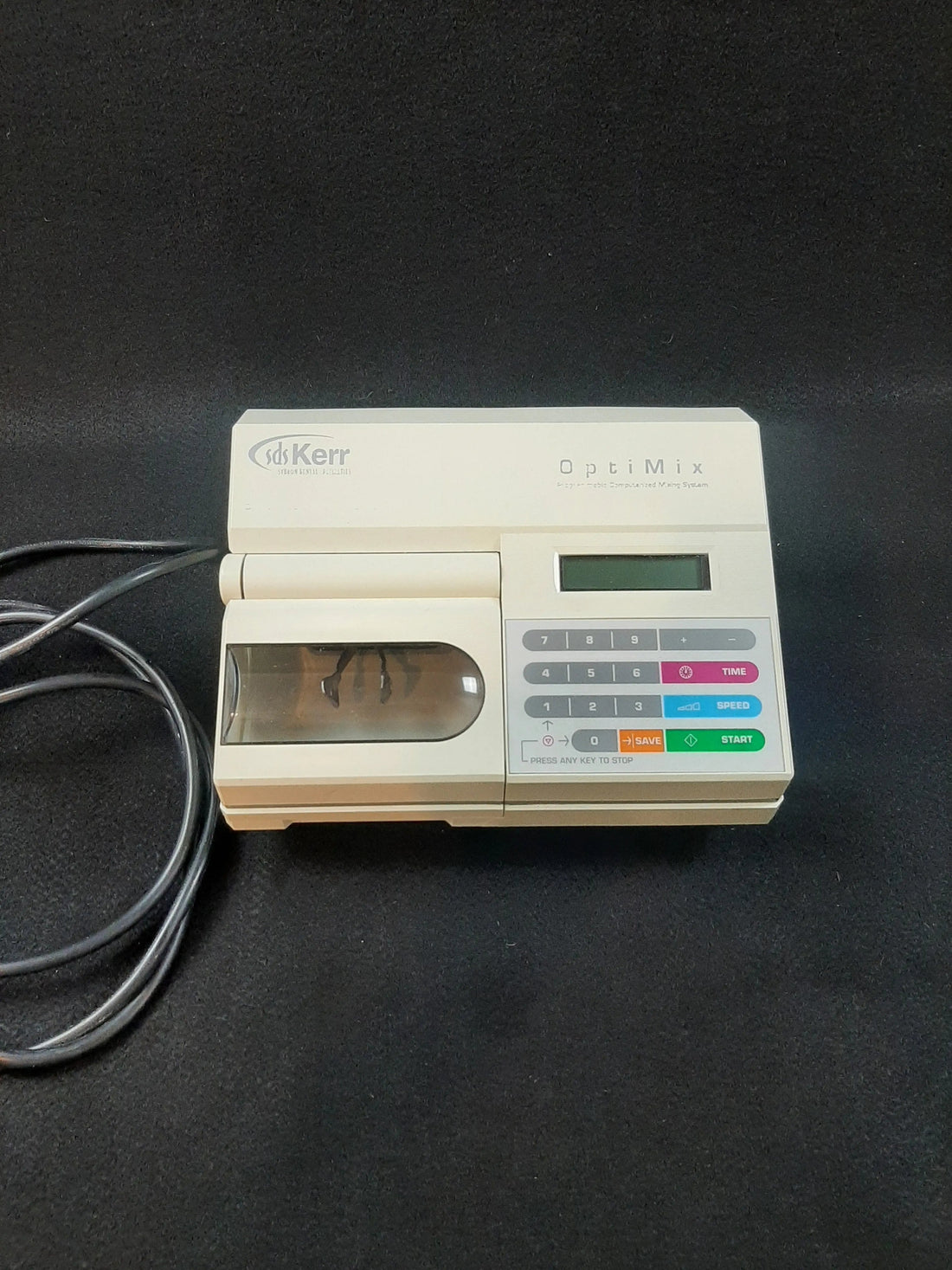 SDS Kerr OptiMix Model 100 front view: blank green LCD, numeric keypad with TIME, SPEED, SAVE and START keys, tinted capsule chamber at left.