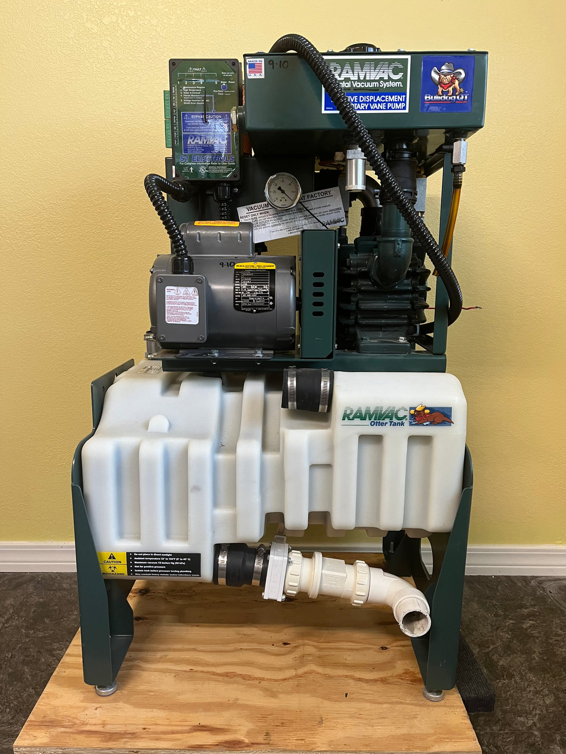 Ramvac Bulldog QT1 dental vacuum system standing on a pallet — green frame, white poly separator tank, Baldor motor and rotary vane pump mounted above