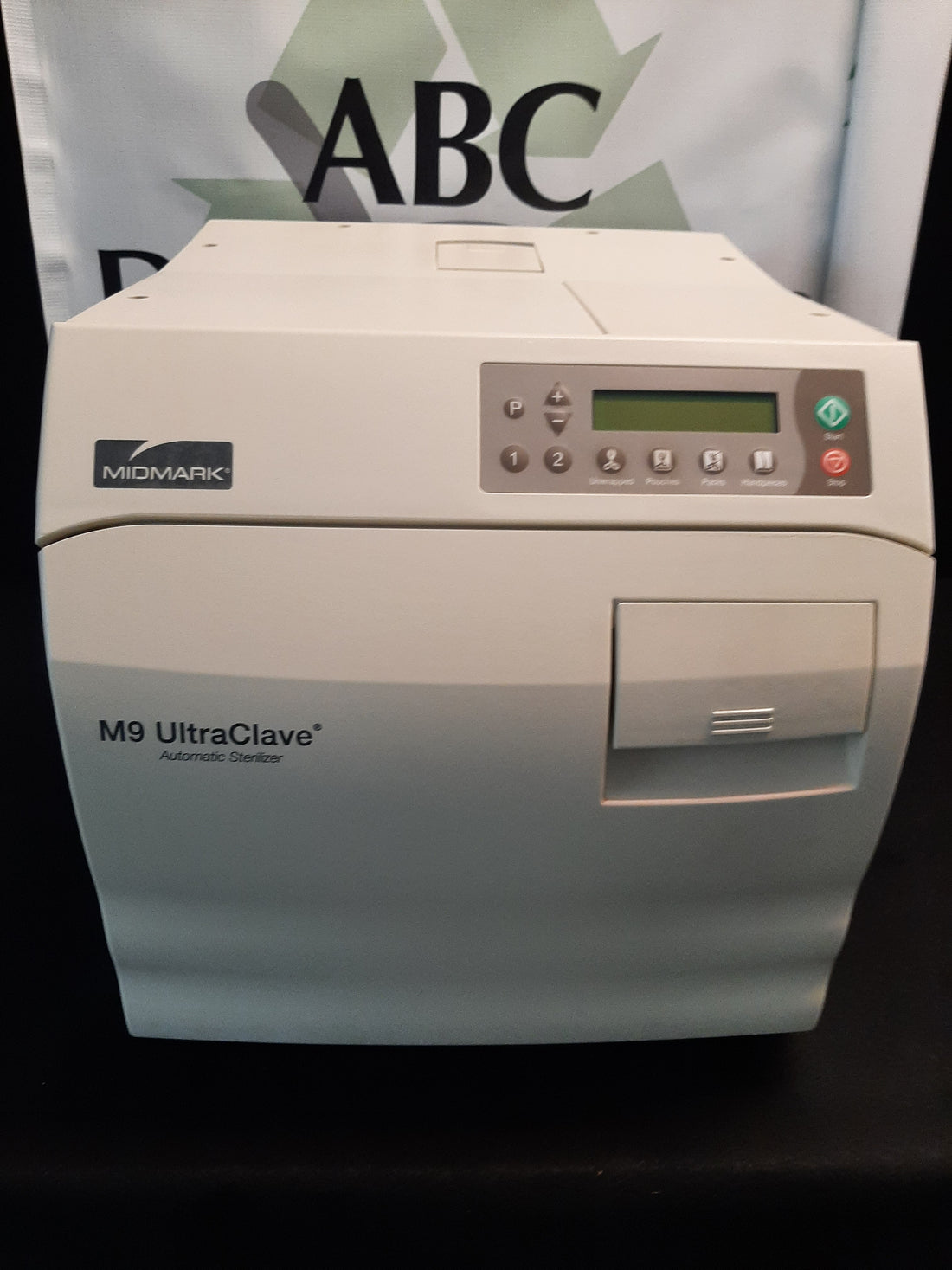 Midmark M9 UltraClave automatic sterilizer, front view with door closed, LCD control panel and M9 UltraClave badge on a black backdrop.
