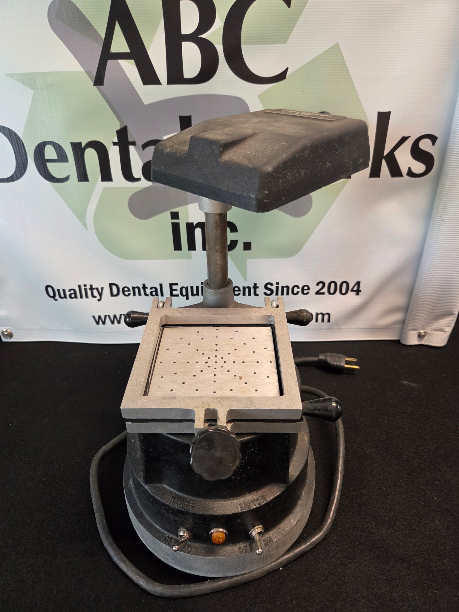 Buffalo Dental vacuum former with the heater hood raised on its center post, showing the spring-loaded forming frame and perforated platen