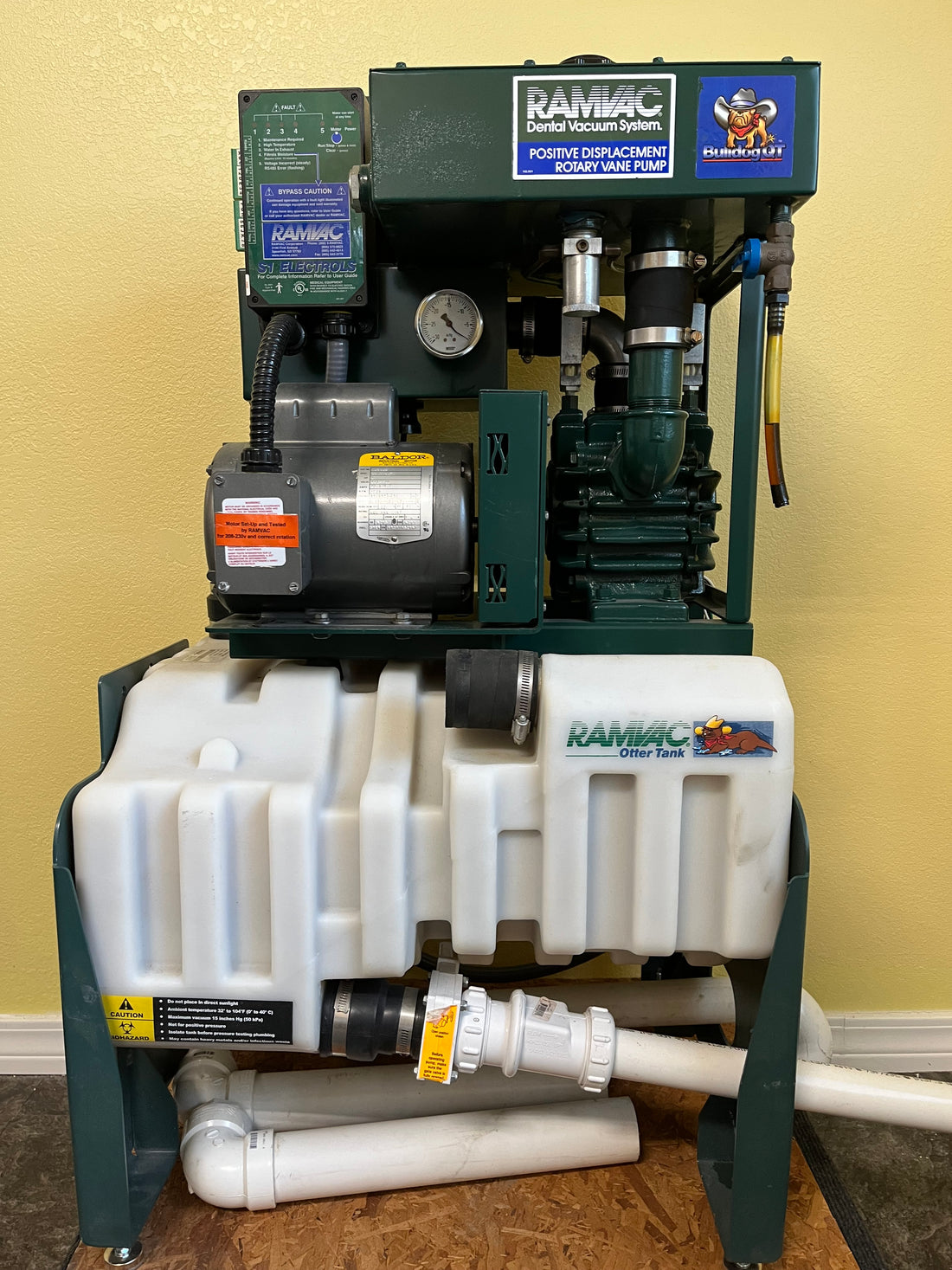 Ramvac Bulldog QT dental vacuum system, full front view on green steel frame with white separator tank and PVC plumbing.