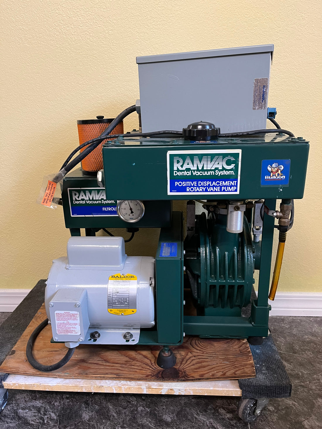 Ramvac Bulldog QT2 dental vacuum system, full front view of green tank, top control box and white Baldor motor on a wood pallet