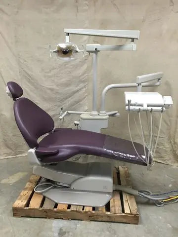 A-dec 1040 Cascade operatory on a shipping pallet: plum upholstered chair, post-mounted operatory light and radius delivery unit with four instrument tubings