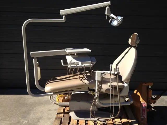 A-dec 1040 Cascade Radius operatory on wooden pallets outdoors: tan upholstered chair, post-mounted light and radius delivery unit with tray