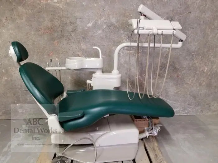 A-dec 1040 Cascade dental chair, left side profile in hunter green upholstery, with cuspidor and over-the-patient delivery, sitting on a shipping pallet.