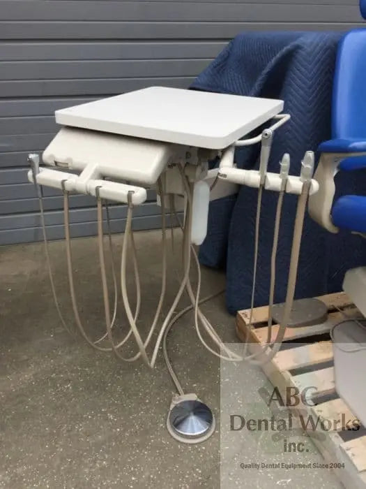 A-dec 3171 wall-mount delivery unit with handpiece tubing and instrument holders, shown beside a dental chair