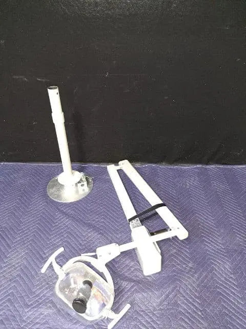 A-dec 6300 ceiling mount light shown disassembled on a blue blanket: ceiling post upright beside the folded arm and light head