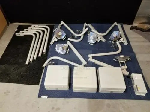 Lot of five Midmark Radius operatory light heads with their arms, plus three beige control boxes, laid out on a blanket