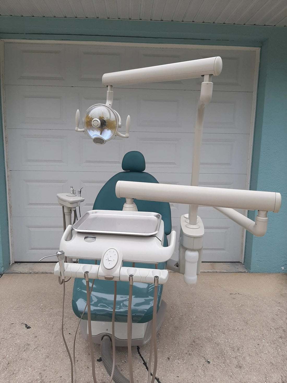 Midmark UltraComfort ProCenter operatory package in teal upholstery — chair, over-the-patient delivery arm and operating light, photographed outdoors