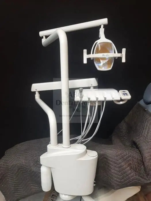 Pelton & Crane Alliance 1250 post-mounted delivery unit with the LF II operatory light on the upper arm, standing on its base against a dark backdrop