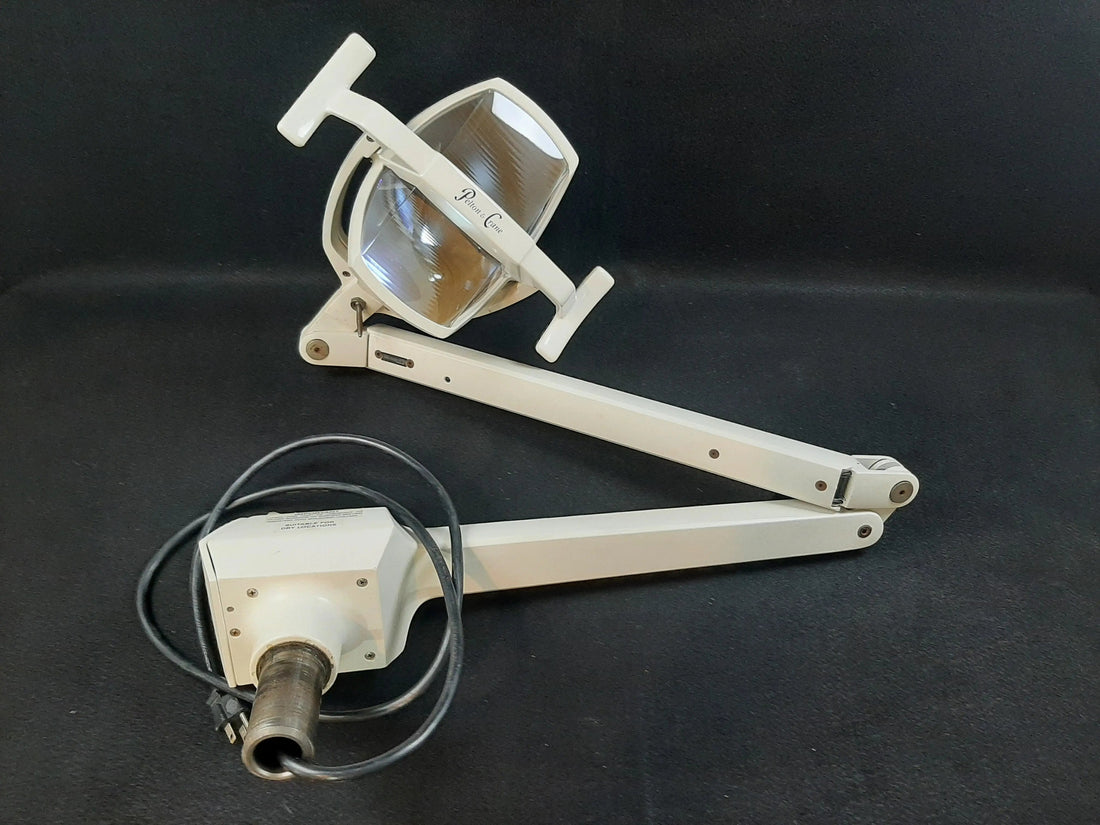 Pelton & Crane LF II operatory light fully detached and laid on a dark cloth: light head, two-section arm and post yoke with coiled power cable.
